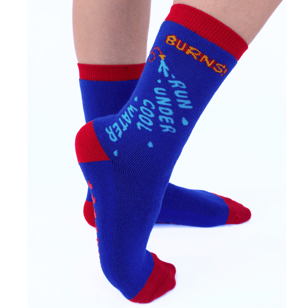 Feet showcasing 'BURNS! Run Under Cool Water' hospital sock design.