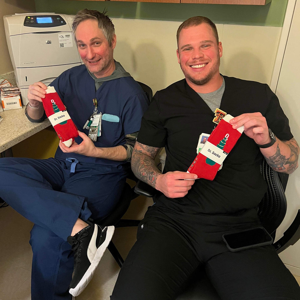 Two cheerful nurses at the hospital, proudly displaying their fun grip socks during a break