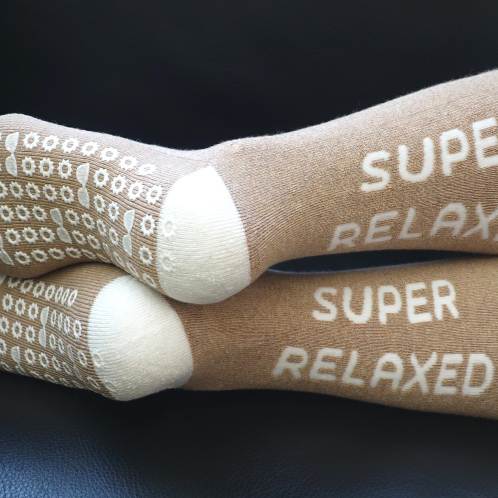 Person lounging on a couch with 'Super Relaxed' hospital sock on
