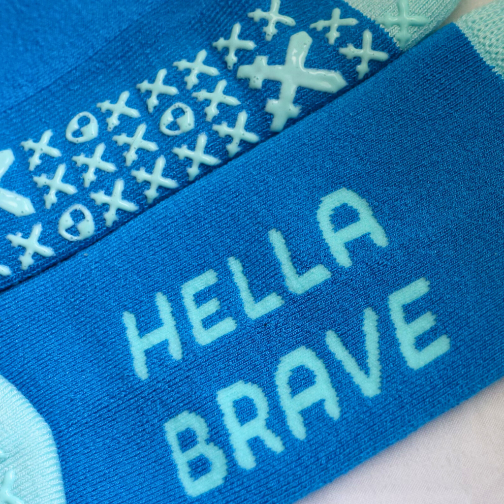 Close-up of 'Hella brave' text on hospital sock.