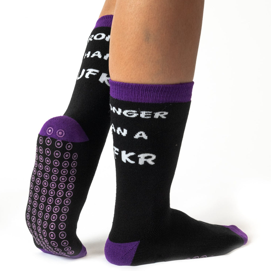 Purple grippy socks for hospital use with 'stronger than a mufkr' message, shown on someone's feet.